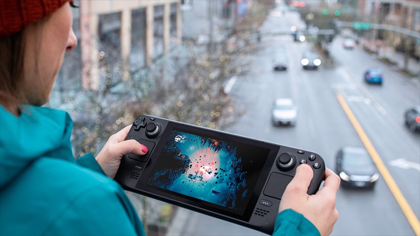 Una mujer jugando con una consola Steam Deck en la calle.