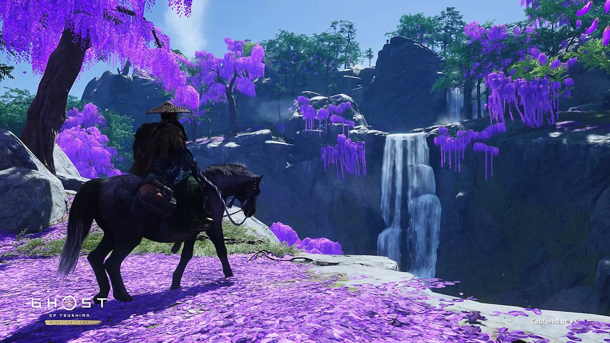 El protagonista de Ghost of Tsushima pasea a caballo por un campo de flores.